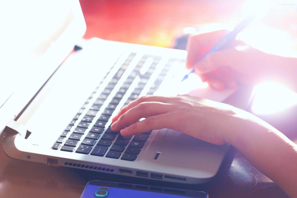 A hand typing on a laptop, representing writing and research behind our blog
