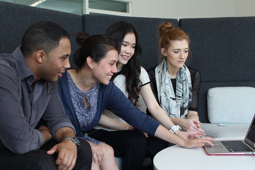 A small group of learners reviewing course material together on a laptop